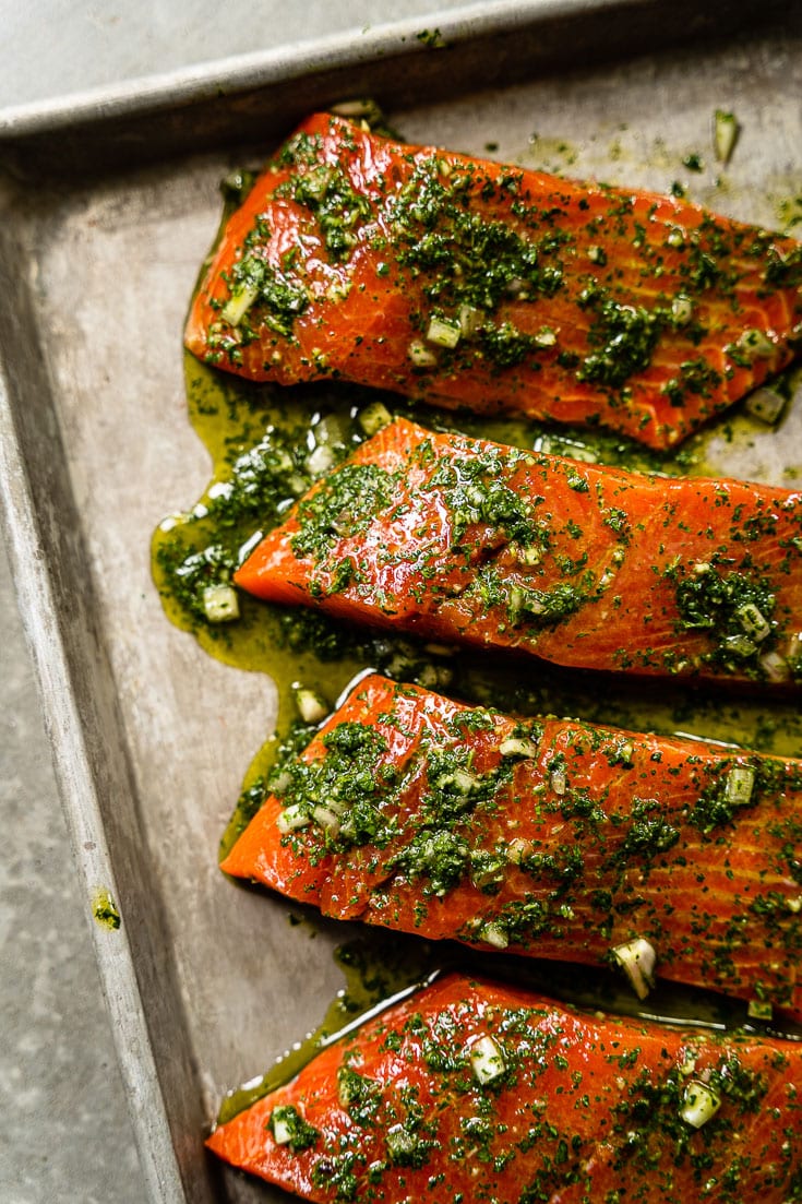 alaskan salmon filets on sheet pan marinating with chimichurri vertical