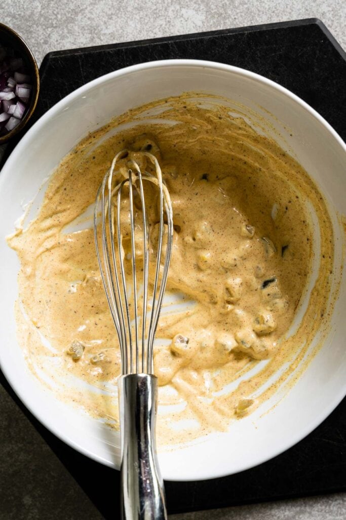 american potato salad dressing in bowl with whisk