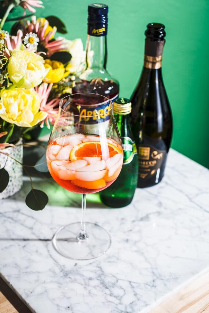 aperol spritz cocktail on white marble with bottles