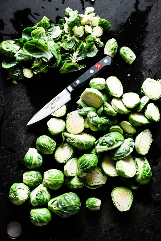 Brussels sprouts cleaned, trimmed and halved on cutting board