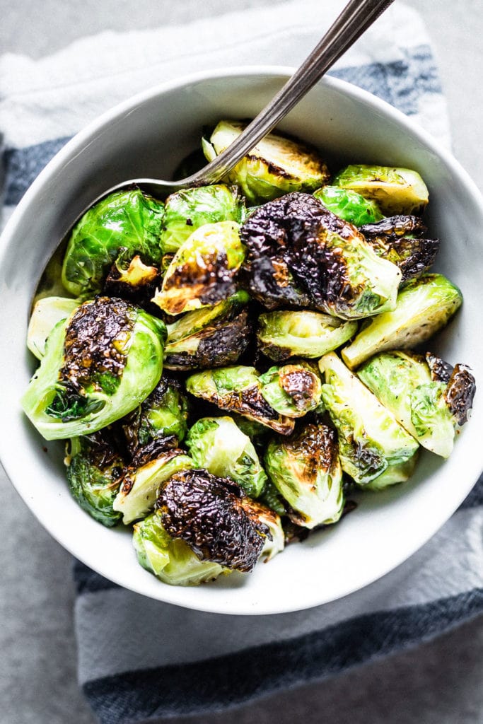 Crispy roasted brussels sprouts in bowl with serving spoon