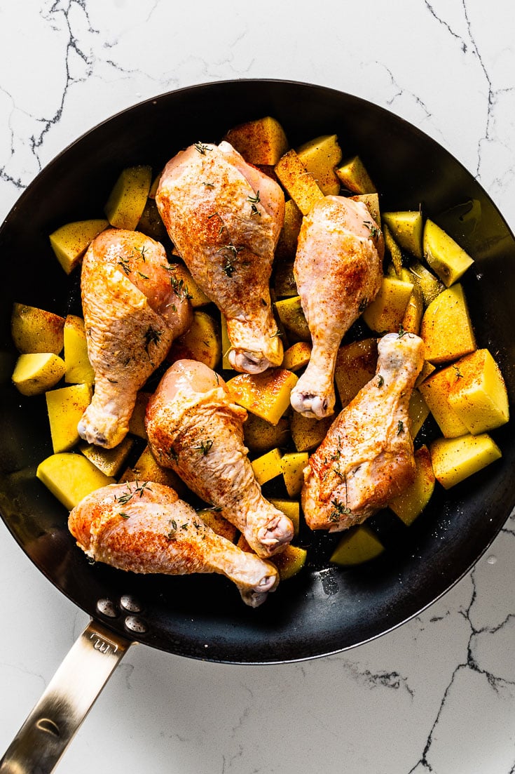 chicken drumsticks with potatoes in skillet overhead