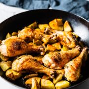 chicken drumsticks with potatoes in skillet side view