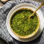 Chimichurri sauce in a bowl with a gold spoon