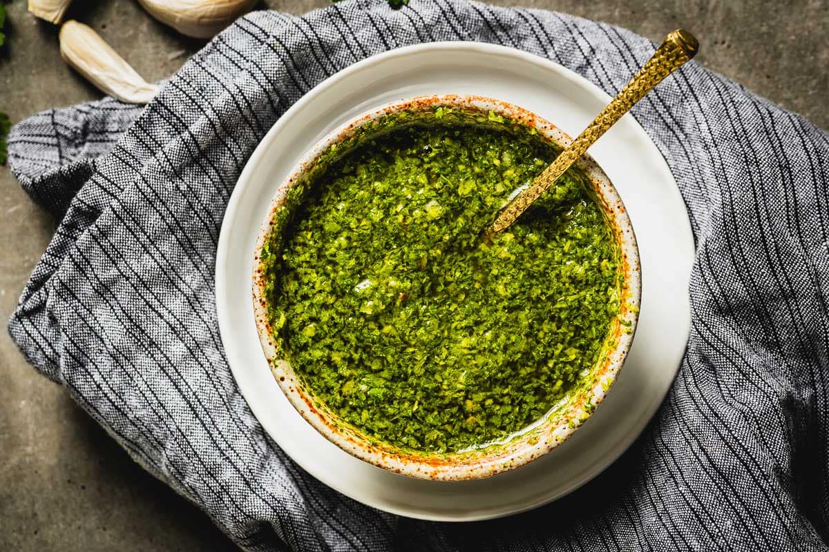 Chimichurri sauce in a bowl with a gold spoon