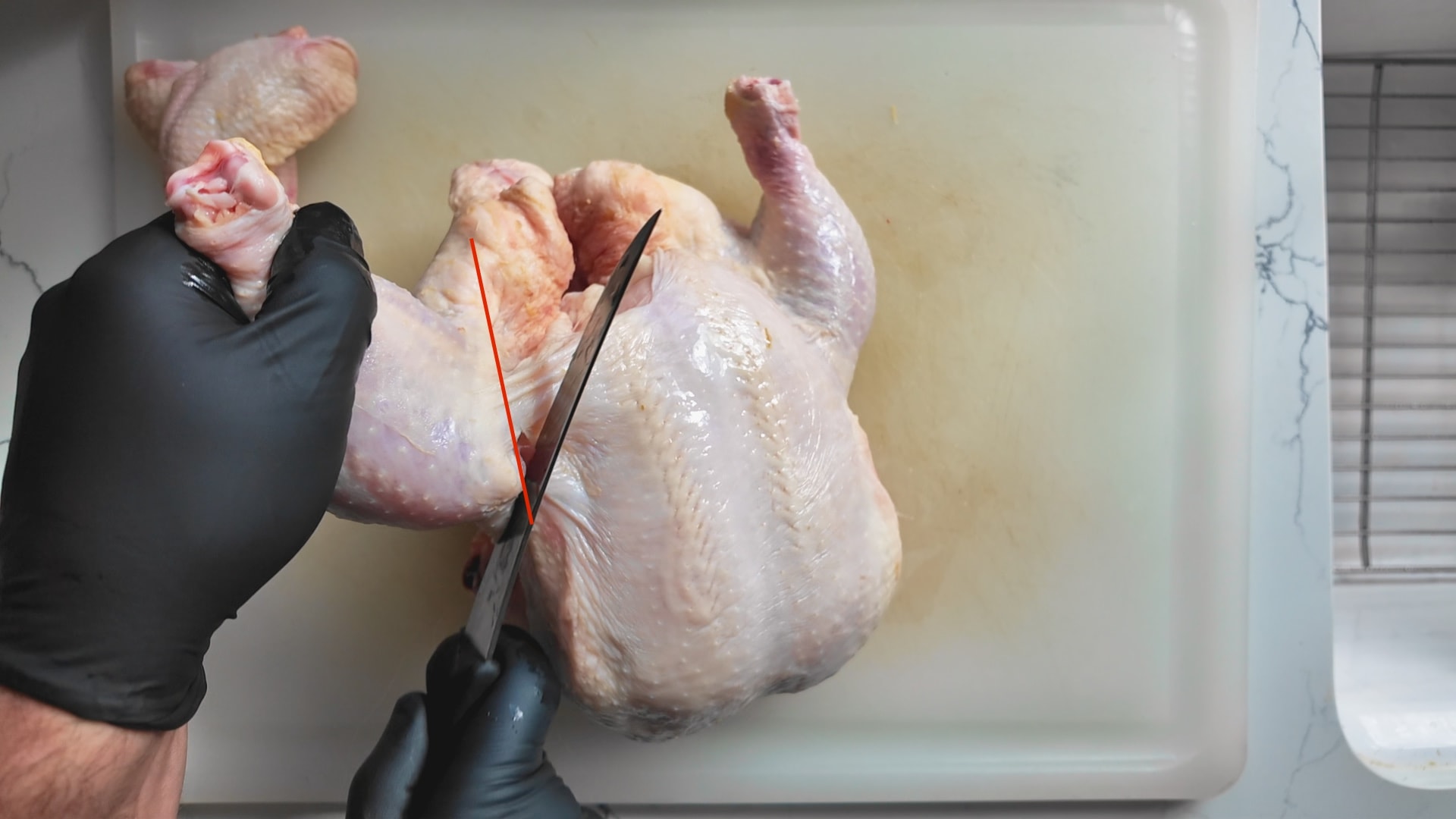 cutting the leg and thigh off a whole chicken
