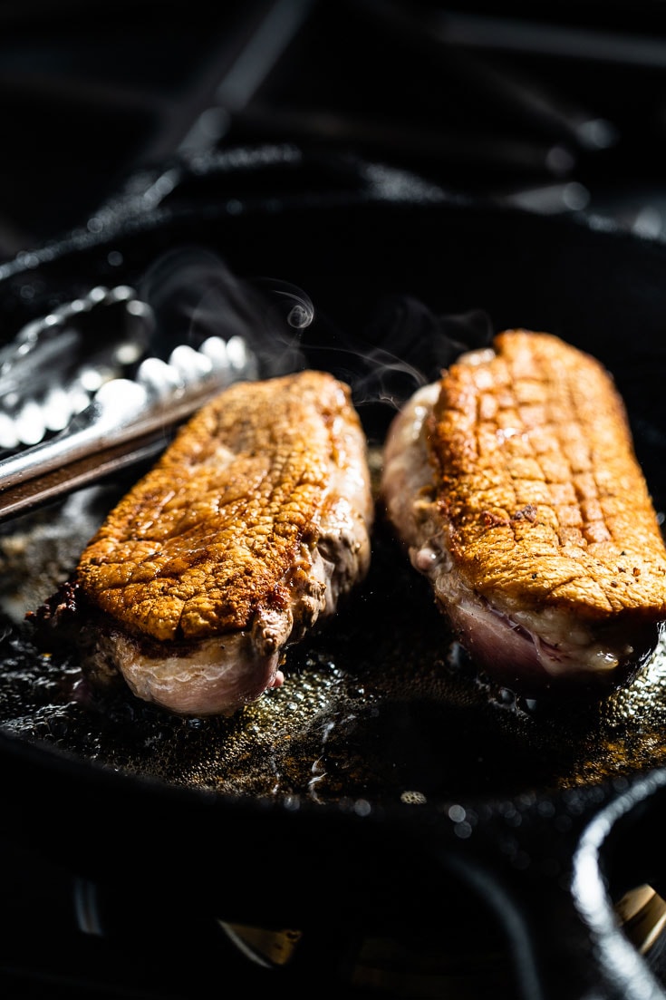 duck breasts searing in skillet vertical