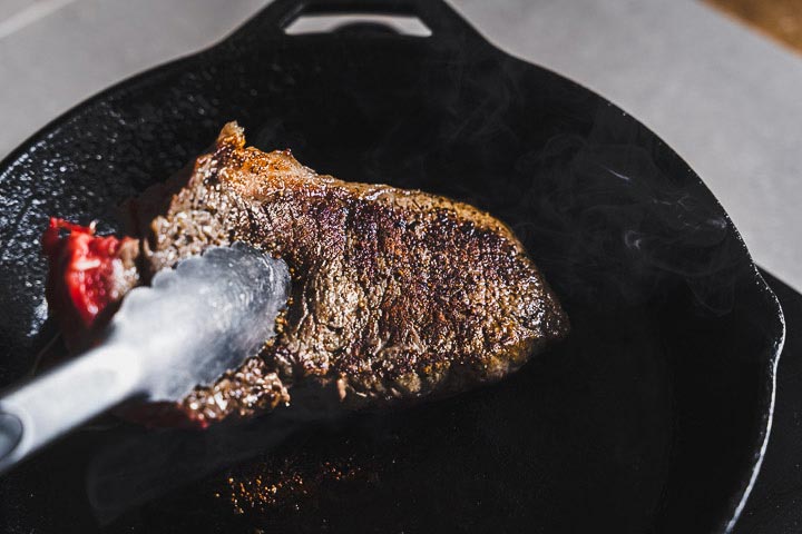 flipping New York Strip Steak with tongs