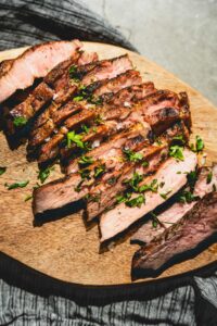 grilled pork steaks sliced on a cutting board vertical