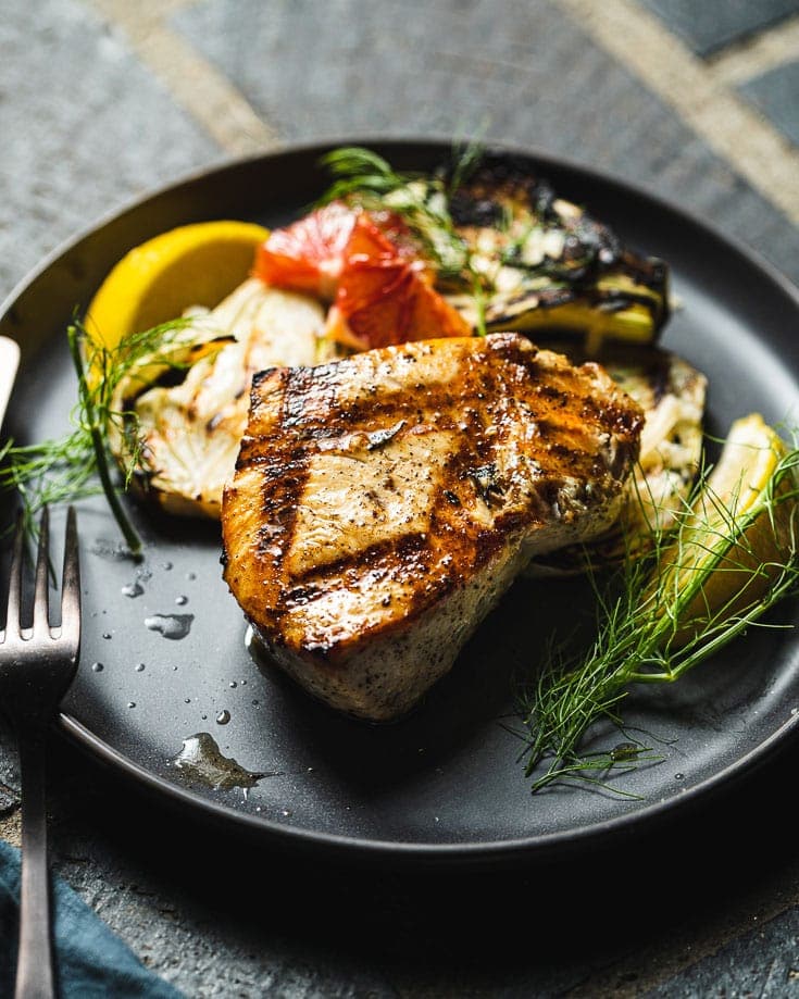 grilled swordfish on plate with lemon and fennel