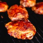 juicy smoked chicken thighs in smoker vertical