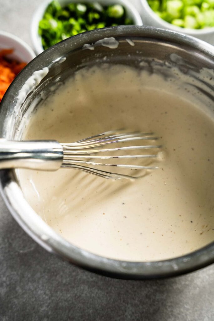 macaroni salad dressing with whisk in bowl