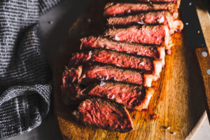 new york strip steak sliced on cutting board featured horizontal