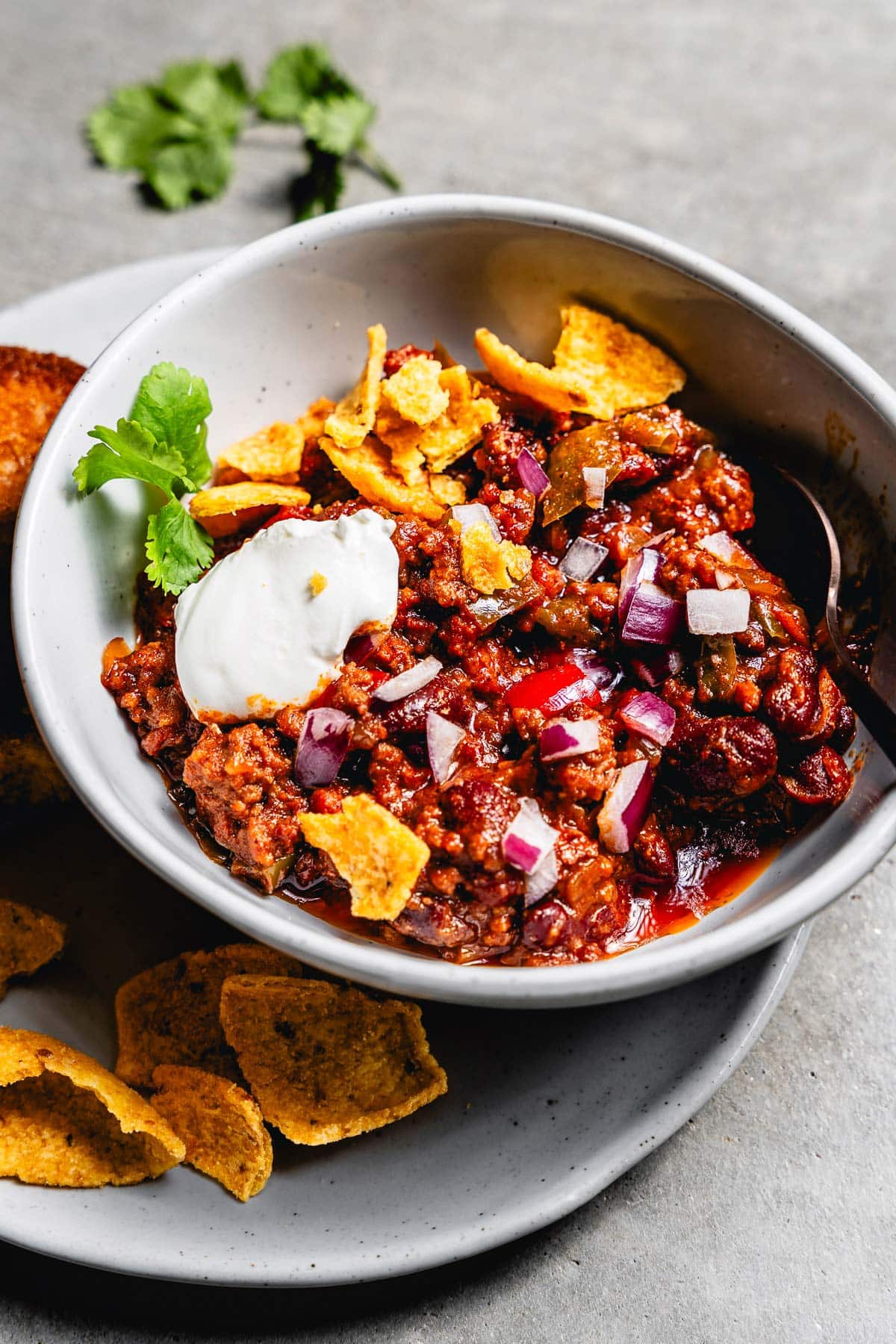 over the top chili in a bowl with toppings vertical close up