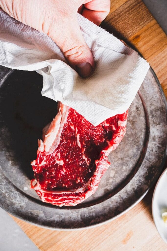 patting a New York Strip Steak dry with paper towel