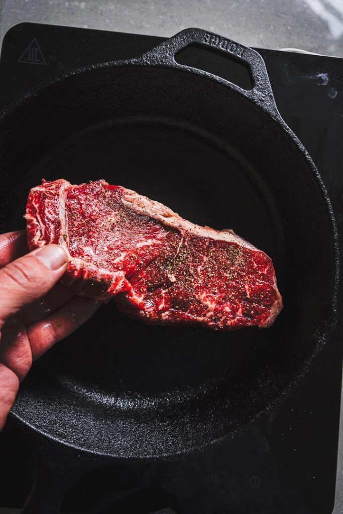 placing New York Strip Steak in cat iron skillet