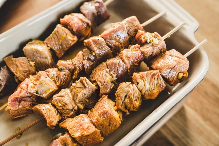 placing marinated lamb on skewers