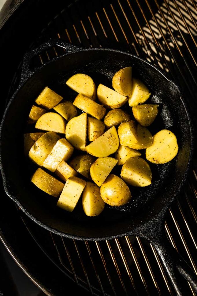 potatoes cooking in a skillet on the grill