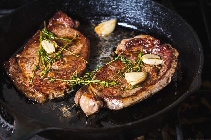 rib eye steaks butter basted in skillet horizontal