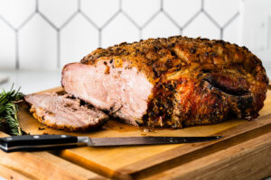 roast pork shoulder sliced on cutting board vertical