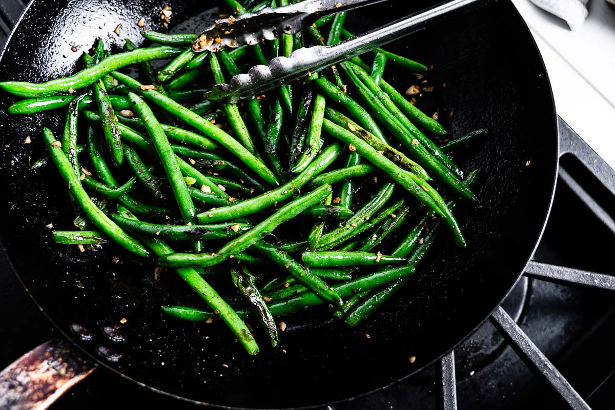 sauteeing green beans in a skillet with garlic