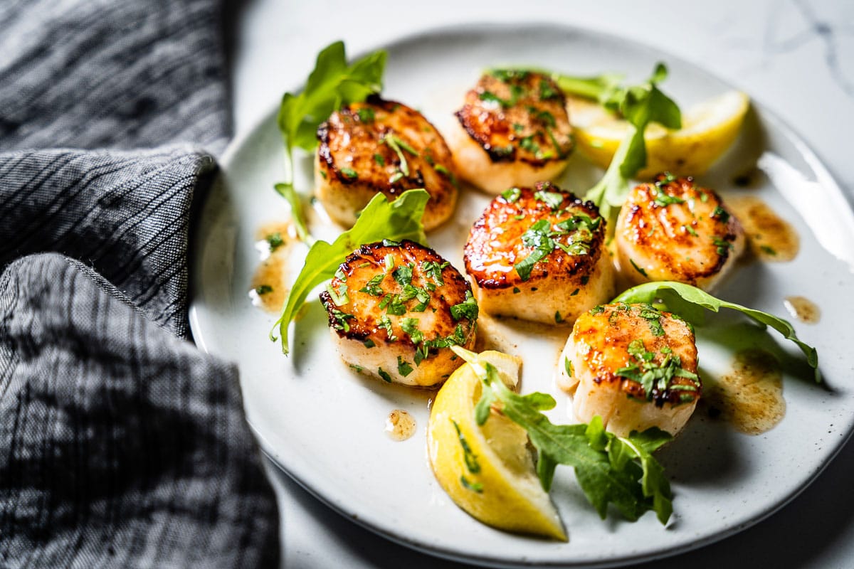 seared scallops on plate with arugula side view 2