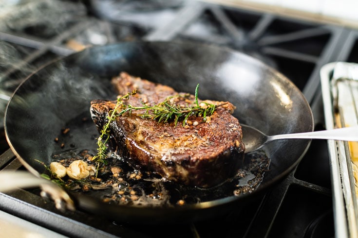 searing bone in rib eye for reverse sear with herbs horizontal