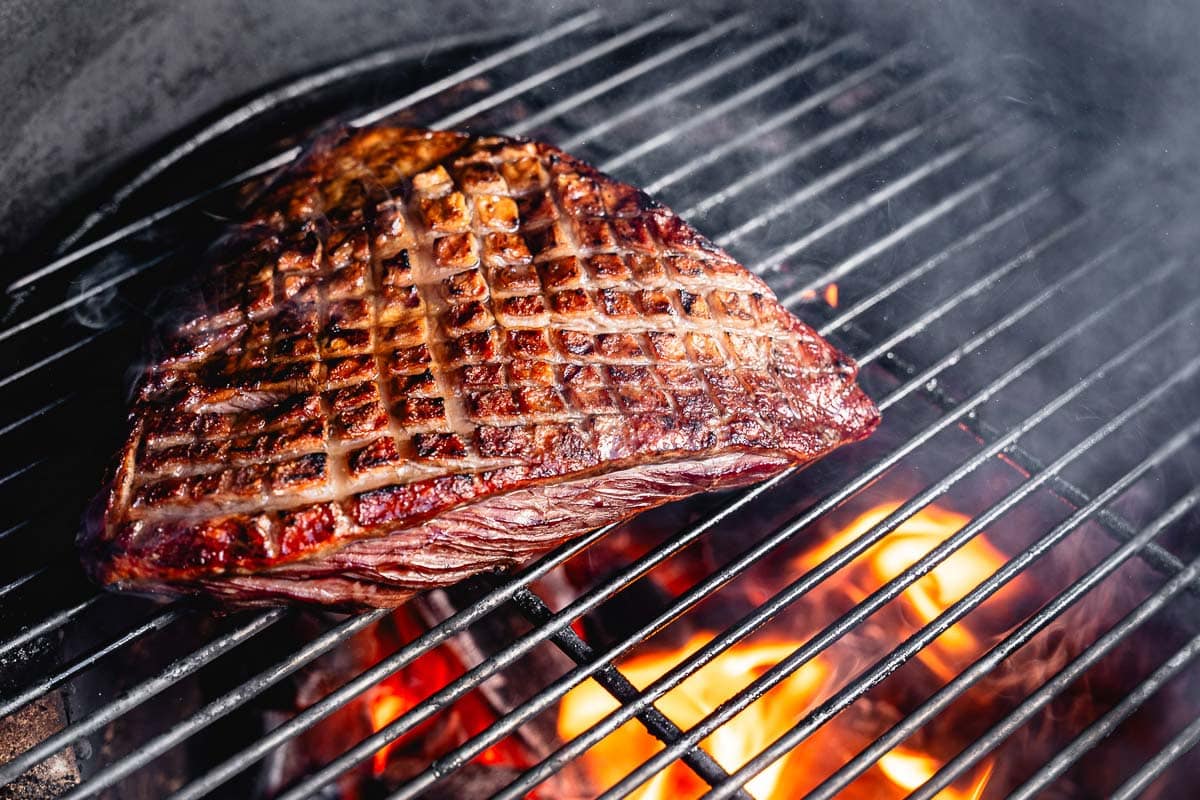 searing picanha steak in charcoal grill
