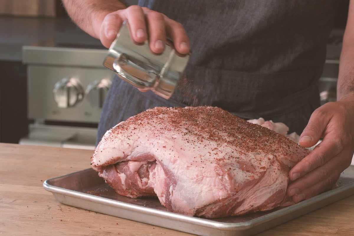 Seasoning pork shoulder with dry rub for smoking