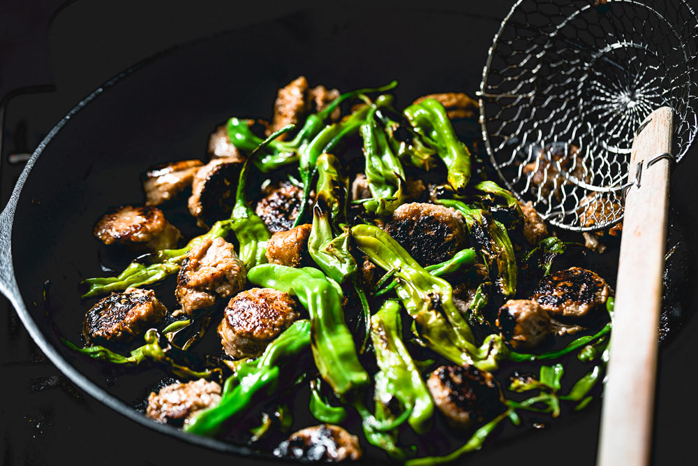 Shishito Peppers and Sausage in a cast iron skillet