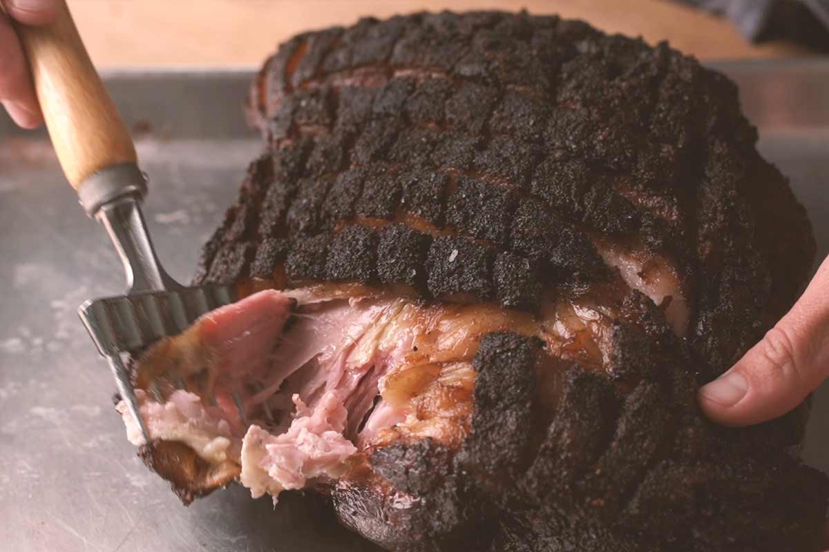 Shredding smoked pork shoulder with ice fork.