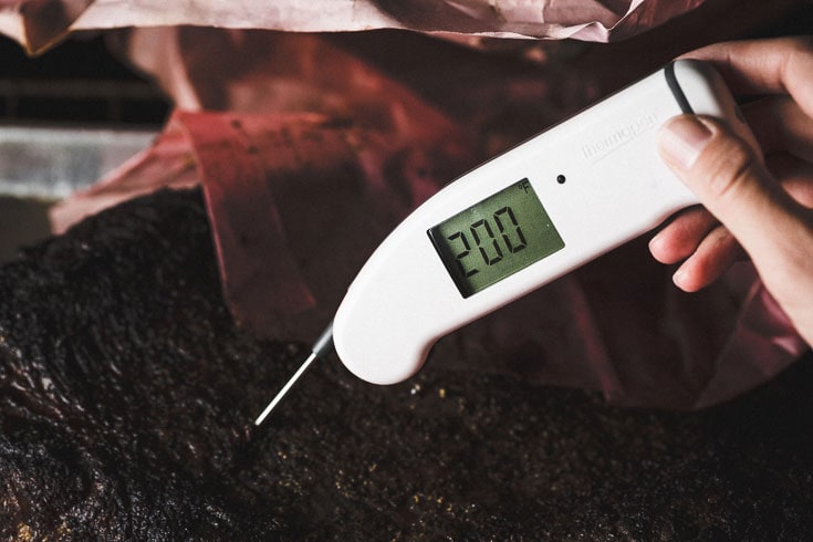 Checking brisket temperature with meat probe thermometer 